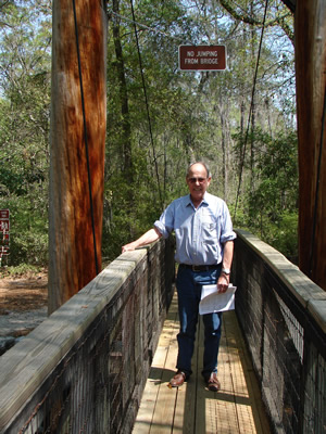 Harold Schiffman, having arrived at the 2009 Suwannee Banjo Camp, walks across the Santa Fe River and cheerfully obeys the bridge's sign: "NO JUMPING FROM BRIDGE." Suwannee Banjo Camp, O'Leno State Park, Florida (20 March 2009)